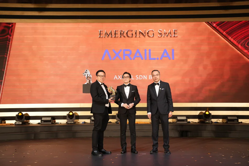 Axrail receiving the Golden Bull trophy on stage under the Emerging SME award screen